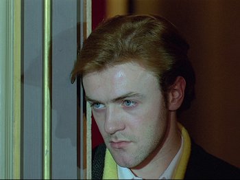 Movie still from “First Name: Carmen” (1983), directed by Jean-Luc Godard – A person wearing a suit and tie; Close Up shot, Low angle