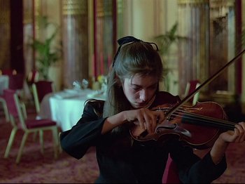 Movie still from “First Name: Carmen” (1983), directed by Jean-Luc Godard – A woman playing a violin in a restaurant; Medium shot, Low angle