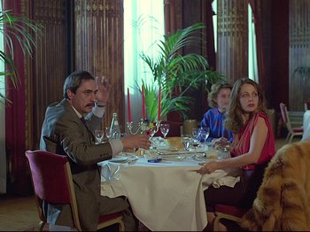 Movie still from “First Name: Carmen” (1983), directed by Jean-Luc Godard – A group of people sitting around a table with wine glasses; Medium shot, Over the shoulder angle