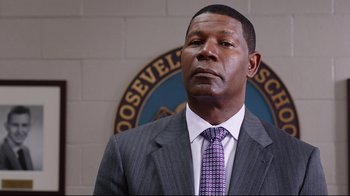 A man wearing a suit and tie standing in front of a sign