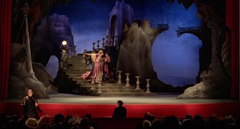 Movie still from “Fitzcarraldo” (1982), directed by Werner Herzog – A scene of a stage with a man and a woman; Extreme Wide shot, High angle