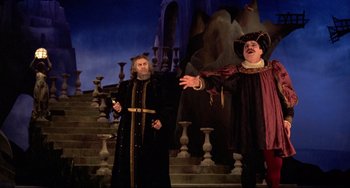 Movie still from “Fitzcarraldo” (1982), directed by Werner Herzog – Two men dressed in medieval costumes singing on stage; Wide shot, Low angle