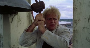 Movie still from “Fitzcarraldo” (1982), directed by Werner Herzog – A man holding on to a metal object with his hands; Close Up shot, Low angle