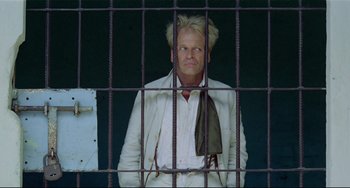 Movie still from “Fitzcarraldo” (1982), directed by Werner Herzog – A man standing behind bars in front of a window; Medium shot, Low angle