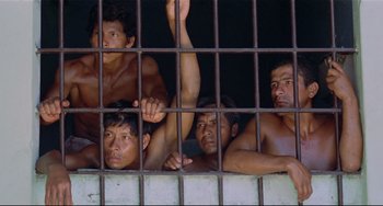 Movie still from “Fitzcarraldo” (1982), directed by Werner Herzog – A group of men sitting on top of a metal fence; Medium shot, High angle
