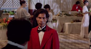 Movie still from “Fitzcarraldo” (1982), directed by Werner Herzog – A man in a red jacket and a bow tie; Medium shot, Over the shoulder angle