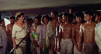 Movie still from “Fitzcarraldo” (1982), directed by Werner Herzog – A group of men standing next to each other in a room; Medium shot, Low angle