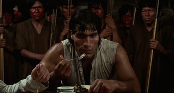 Movie still from “Fitzcarraldo” (1982), directed by Werner Herzog – A man sitting at a table eating food; Medium shot, High angle