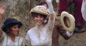 Movie still from “Fitzcarraldo” (1982), directed by Werner Herzog – A woman in a white dress and a hat waving; Medium shot, Over the shoulder angle