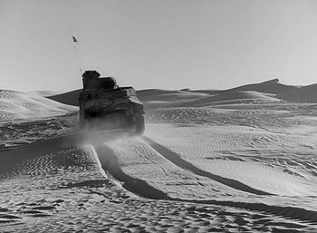 Movie still from “Five Graves to Cairo” (1943), directed by Billy Wilder – A tank driving through the desert on a sunny day; Extreme Wide shot, High angle