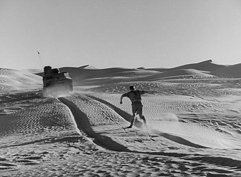 Movie still from “Five Graves to Cairo” (1943), directed by Billy Wilder – A man is running through the snow on a vehicle; Wide shot, High angle