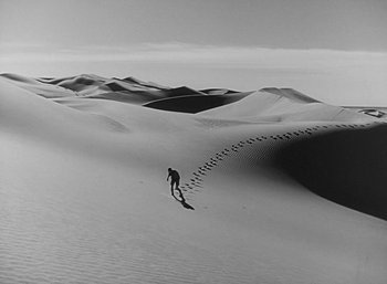 Movie still from “Five Graves to Cairo” (1943), directed by Billy Wilder – A person is skiing down a hill in the desert; Extreme Wide shot, High angle