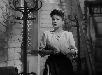 Movie still from “Five Graves to Cairo” (1943), directed by Billy Wilder – A black and white photo of a woman standing in front of a brick wall; Medium shot, Low angle