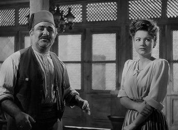 Movie still from “Five Graves to Cairo” (1943), directed by Billy Wilder – A man and a woman standing next to each other; Medium shot, Low angle