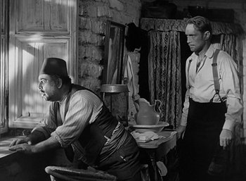 Movie still from “Five Graves to Cairo” (1943), directed by Billy Wilder – A man and a woman standing next to each other in front of a table; Medium shot, Over the shoulder angle