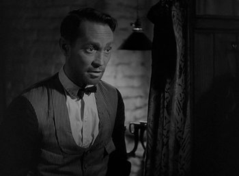 Movie still from “Five Graves to Cairo” (1943), directed by Billy Wilder – A black and white photo of a man in a suit and tie; Close Up shot, Over the shoulder angle