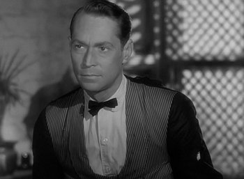 Movie still from “Five Graves to Cairo” (1943), directed by Billy Wilder – An old photo of a man wearing a suit and bow tie; Close Up shot, Low angle