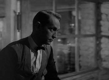 Movie still from “Five Graves to Cairo” (1943), directed by Billy Wilder – A black and white photo of a man in a suit and tie; Close Up shot, Over the shoulder angle