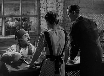 Movie still from “Five Graves to Cairo” (1943), directed by Billy Wilder – A group of people standing around a table with food on top of it; Medium shot, Over the shoulder angle