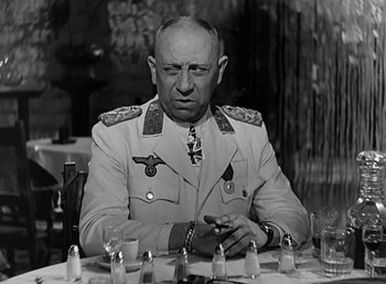 Movie still from “Five Graves to Cairo” (1943), directed by Billy Wilder – An old photo of a man sitting at a table; Close Up shot, Over the shoulder angle