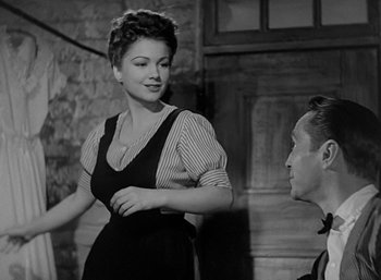 Movie still from “Five Graves to Cairo” (1943), directed by Billy Wilder – A woman standing next to a man in a room with a brick wall; Medium shot, Over the shoulder angle