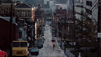 Movie still from “Flashdance” (1983), directed by Adrian Lyne – A view of a city street with cars parked on the side of the road; Extreme Wide shot, High angle