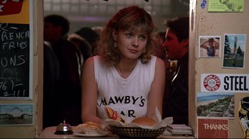 Movie still from “Flashdance” (1983), directed by Adrian Lyne – A woman sitting in front of a plate of food; Close Up shot, Over the shoulder angle