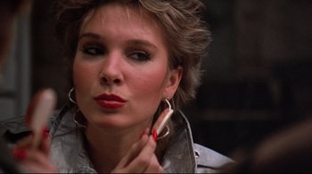 Movie still from “Flashdance” (1983), directed by Adrian Lyne – A person holding a cell phone to their ear; Close Up shot, Over the shoulder angle