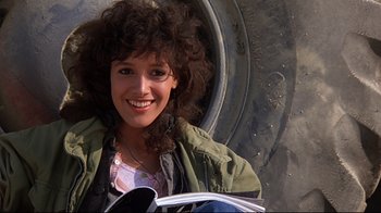 Movie still from “Flashdance” (1983), directed by Adrian Lyne – A woman with curly brown hair is smiling for the camera; Close Up shot, Low angle