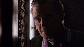 Movie still from “Flashdance” (1983), directed by Adrian Lyne – An older man wearing a priest's outfit looking at the camera; Close Up shot, Low angle