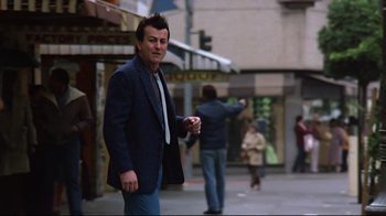 Movie still from “Flashdance” (1983), directed by Adrian Lyne – A man wearing a suit and tie walking down a street; Medium shot, Low angle