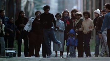 Movie still from “Flashdance” (1983), directed by Adrian Lyne – A group of people standing on the sidewalk; Wide shot, Low angle