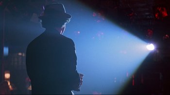 Movie still from “Flashdance” (1983), directed by Adrian Lyne – A man wearing a hat standing in the light; Close Up shot, Low angle