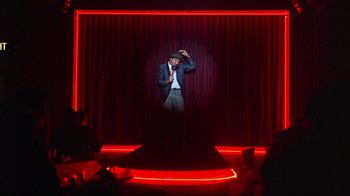 Movie still from “Flashdance” (1983), directed by Adrian Lyne – A man standing in front of a curtain on a stage; Wide shot, Low angle