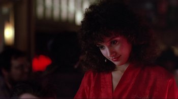 Movie still from “Flashdance” (1983), directed by Adrian Lyne – A woman in a red robe is smiling for the camera; Close Up shot, Low angle