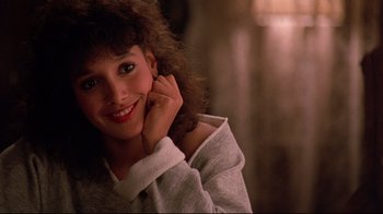 Movie still from “Flashdance” (1983), directed by Adrian Lyne – A young woman smiles while posing for a picture; Close Up shot, Over the shoulder angle