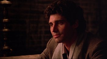 Movie still from “Flashdance” (1983), directed by Adrian Lyne – A man with curly brown hair wearing a suit and tie; Close Up shot, Over the shoulder angle