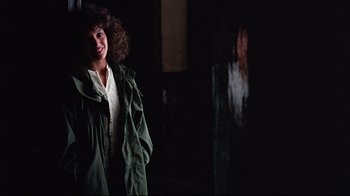 Movie still from “Flashdance” (1983), directed by Adrian Lyne – A woman standing in a dark room with her eyes closed; Medium shot, Over the shoulder angle