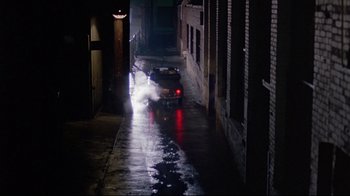 Movie still from “Flashdance” (1983), directed by Adrian Lyne – A car driving down a street at night; Extreme Wide shot, High angle