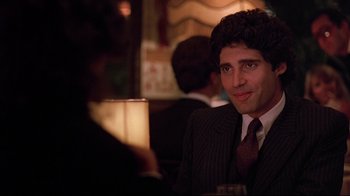 Movie still from “Flashdance” (1983), directed by Adrian Lyne – A man sitting at a table in a suit and tie; Close Up shot, Over the shoulder angle