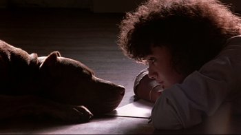 Movie still from “Flashdance” (1983), directed by Adrian Lyne – A woman laying on the ground next to a dog; Close Up shot, High angle
