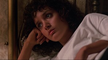 Movie still from “Flashdance” (1983), directed by Adrian Lyne – A woman with curly brown hair laying on a bed; Close Up shot, Low angle