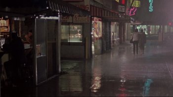 Movie still from “Flashdance” (1983), directed by Adrian Lyne – A person walking down a wet street at night; Extreme Wide shot, High angle