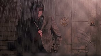 Movie still from “Flashdance” (1983), directed by Adrian Lyne – A man in a suit standing in front of a wall; Medium shot, Low angle