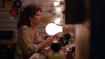 Movie still from “Flashdance” (1983), directed by Adrian Lyne – A woman sitting in front of a mirror in a room; Medium shot, Over the shoulder angle