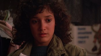 Movie still from “Flashdance” (1983), directed by Adrian Lyne – A woman with curly brown hair wearing a tan jacket; Close Up shot, Low angle