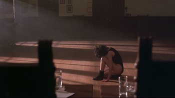 Movie still from “Flashdance” (1983), directed by Adrian Lyne – A person sitting on the floor in a room; Wide shot, Over the shoulder angle