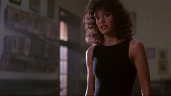 Movie still from “Flashdance” (1983), directed by Adrian Lyne – A woman in a black dress standing in front of a window; Medium shot, Low angle