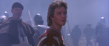 Movie still from “Flesh+Blood” (1985), directed by Paul Verhoeven – A man in a red shirt is standing in the fog; Close Up shot, Low angle