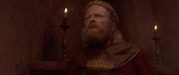 Movie still from “Flesh+Blood” (1985), directed by Paul Verhoeven – A man with a beard and a crown is looking at a lit candle; Close Up shot, Low angle